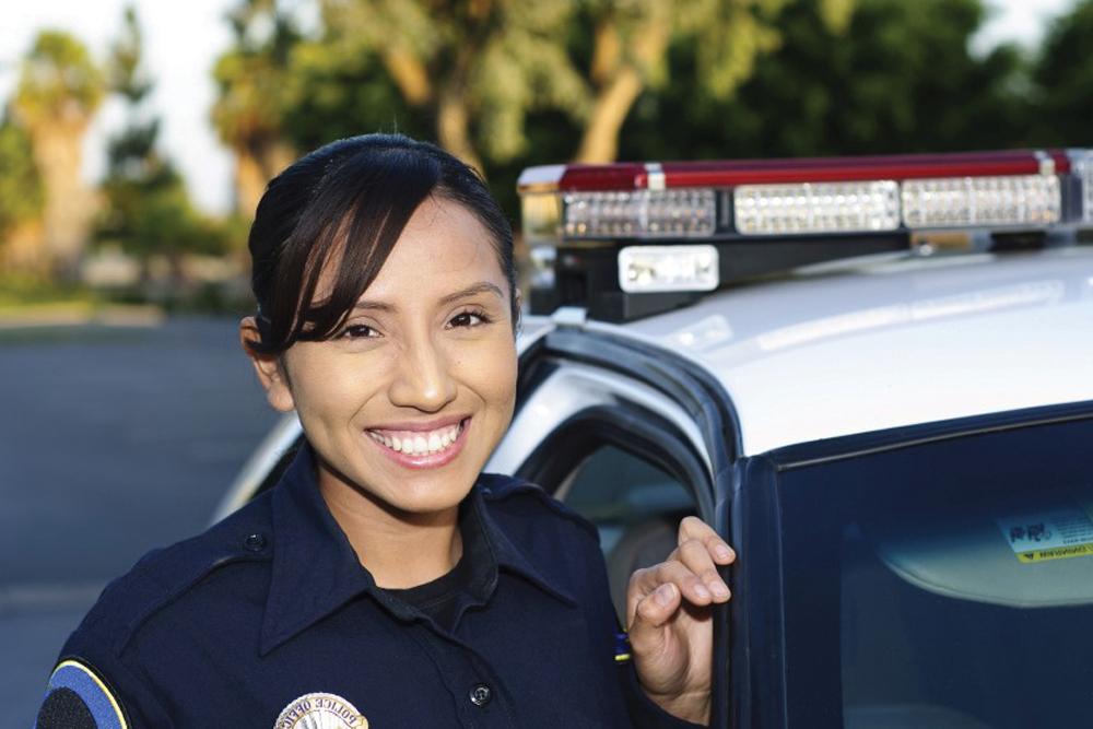 刑事司法 female officer smiling near police car